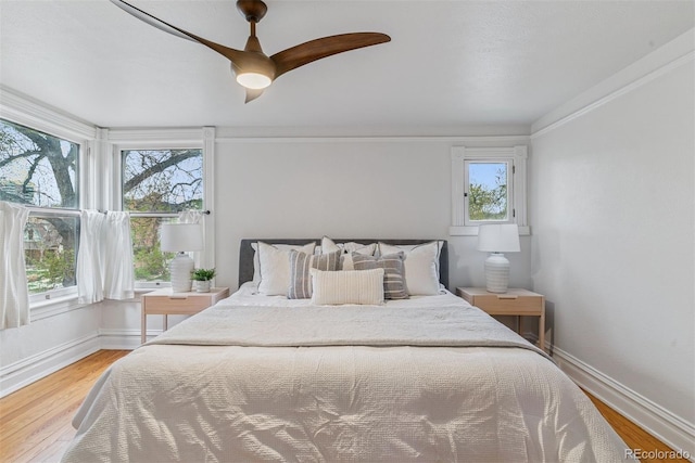 bedroom with a ceiling fan, baseboards, and light wood-style flooring
