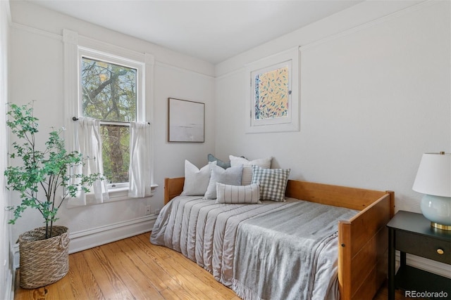 bedroom with wood-type flooring, baseboards, and multiple windows