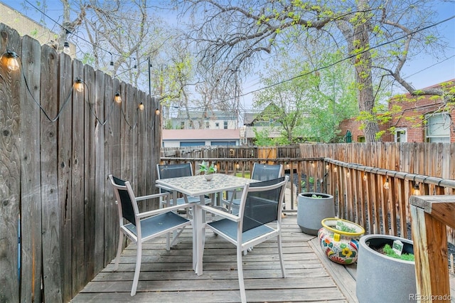 wooden terrace featuring outdoor dining area and a fenced backyard