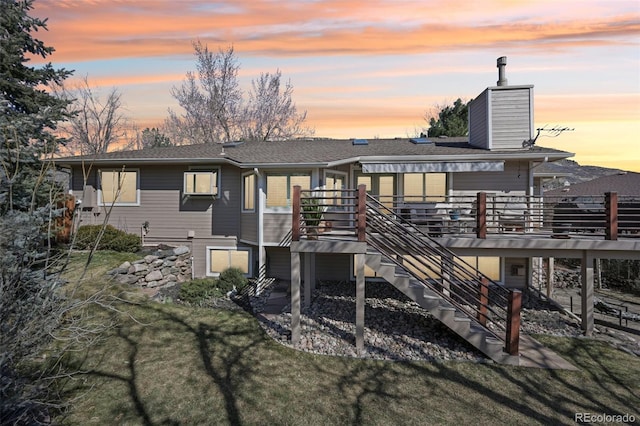 rear view of house featuring a wooden deck, stairway, a chimney, and a yard