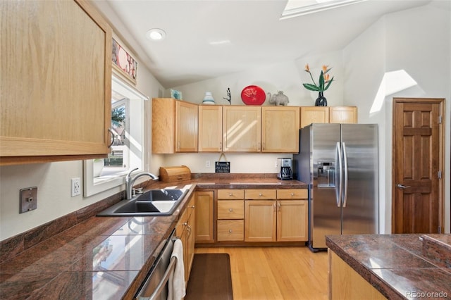 kitchen featuring tile countertops, a sink, stainless steel appliances, vaulted ceiling, and light wood-type flooring