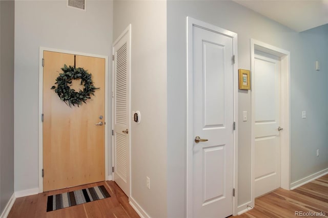 hall featuring baseboards, visible vents, and wood finished floors