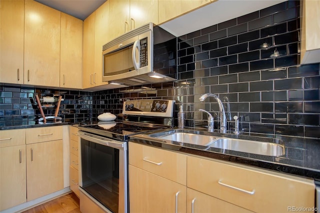 kitchen with light brown cabinets, appliances with stainless steel finishes, decorative backsplash, and dark stone counters