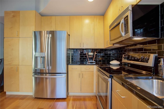 kitchen featuring tasteful backsplash, dark countertops, light wood-style flooring, appliances with stainless steel finishes, and light brown cabinets