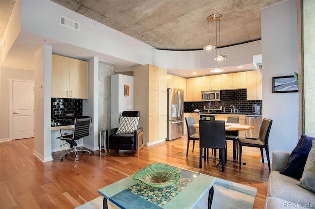 living area with light wood-style floors, visible vents, built in desk, and baseboards