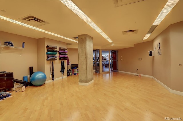 workout area featuring wood finished floors, visible vents, and baseboards