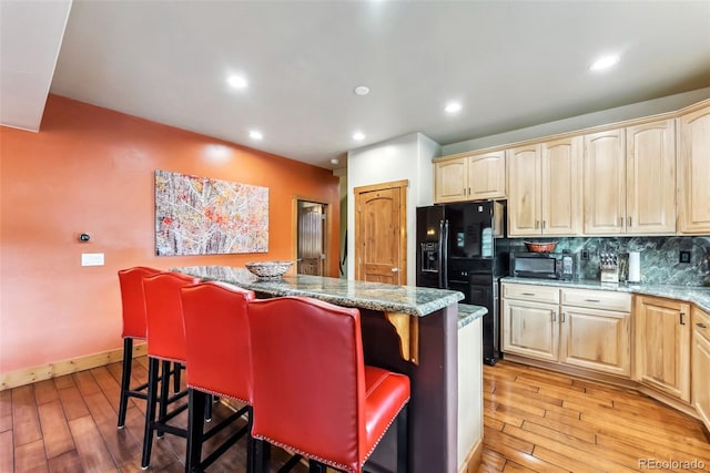 200 Rachel Ln, Breckenridge, CO 80424 - kitchen with light brown cabinetry, black appliances, a center island, a kitchen bar, and light wood-type flooring
