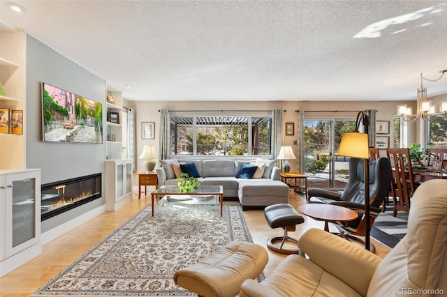 living room with a chandelier, light hardwood / wood-style floors, and a textured ceiling