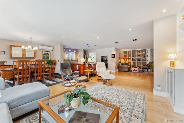 living room with a chandelier, a wall mounted AC, and light wood-type flooring