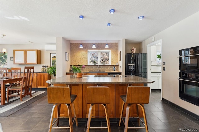 bar featuring sink, dark stone countertops, a wall mounted AC, black appliances, and a textured ceiling