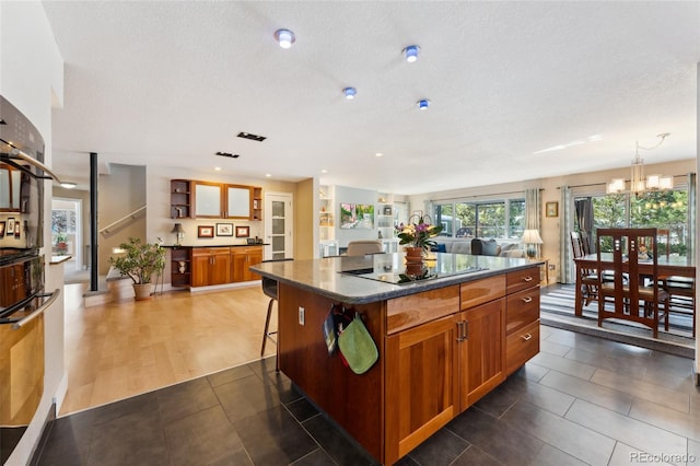 kitchen featuring a kitchen bar, decorative light fixtures, a center island, a notable chandelier, and black electric stovetop