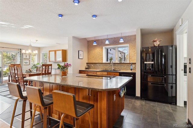 kitchen featuring sink, backsplash, black appliances, and a center island