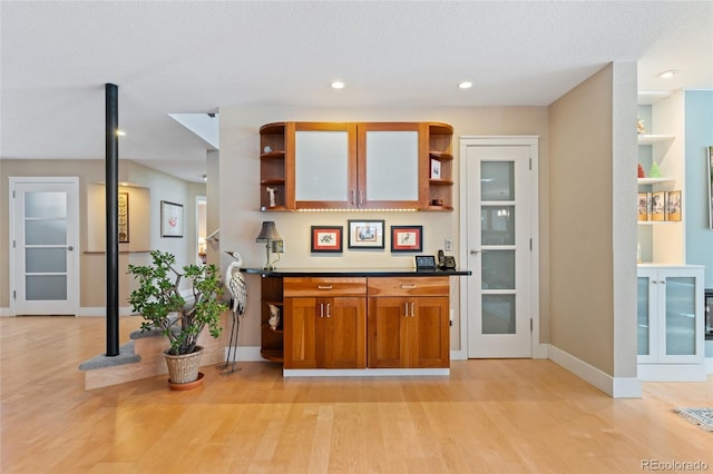 bar featuring french doors, light hardwood / wood-style floors, and a textured ceiling