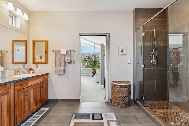 bathroom featuring tile patterned flooring, vanity, baseboard heating, and a shower with shower door