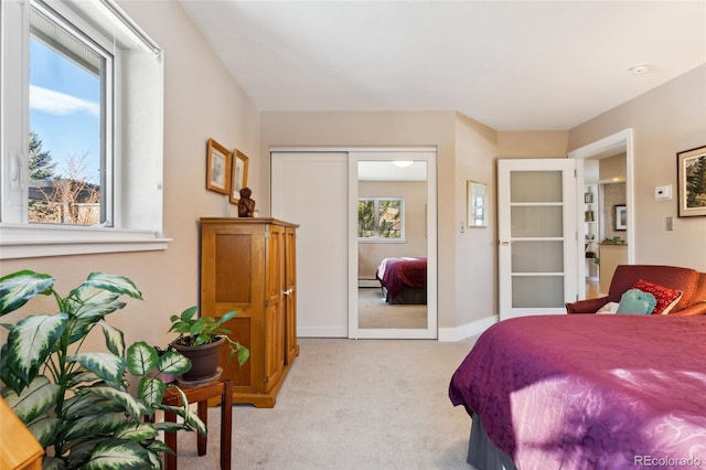 bedroom with a baseboard heating unit, light carpet, and a closet