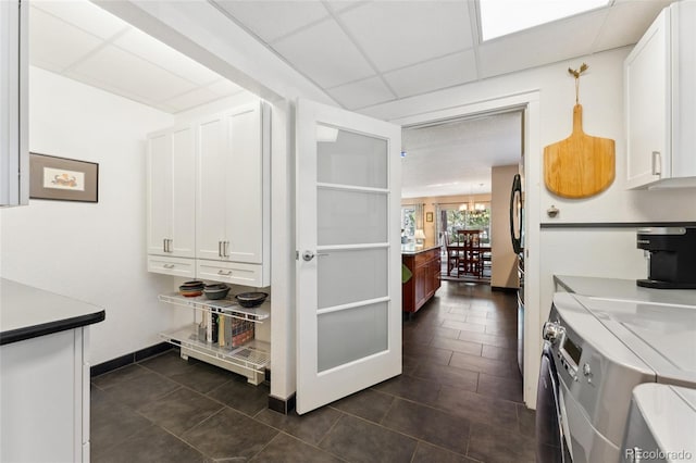 kitchen with white cabinetry, a drop ceiling, an inviting chandelier, and decorative light fixtures