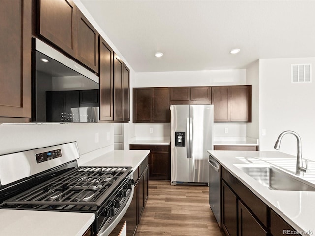 kitchen featuring stainless steel appliances, a sink, visible vents, and dark brown cabinetry