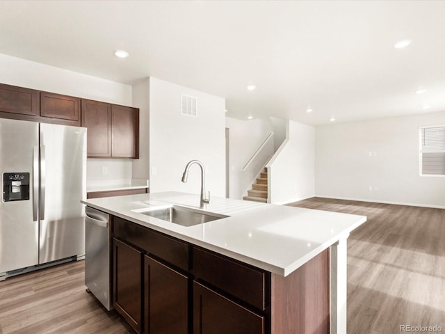 kitchen with light wood-style flooring, stainless steel appliances, a sink, visible vents, and light countertops