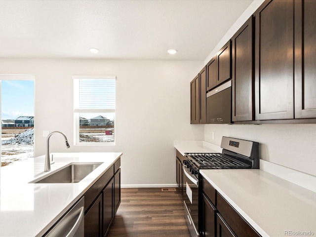 kitchen with stainless steel appliances, light countertops, a sink, and dark brown cabinets