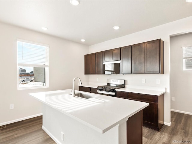 kitchen featuring dark brown cabinetry, gas range, dark wood-style floors, light countertops, and a sink