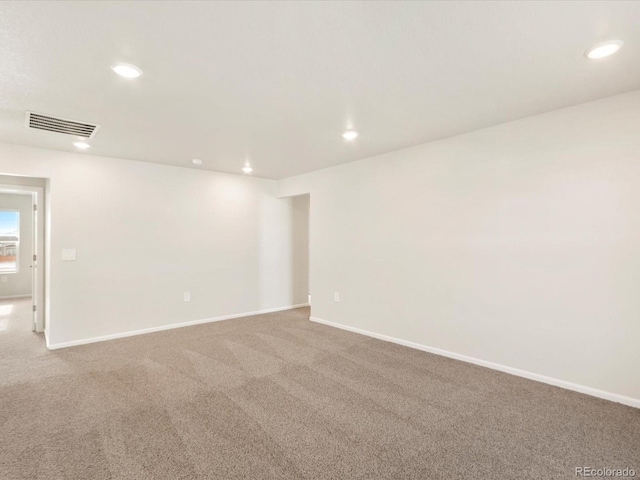 carpeted empty room with baseboards, visible vents, and recessed lighting