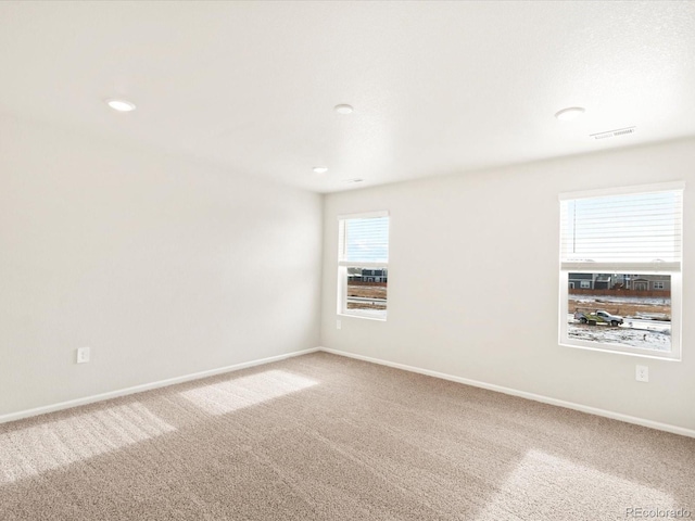 carpeted spare room featuring visible vents and baseboards