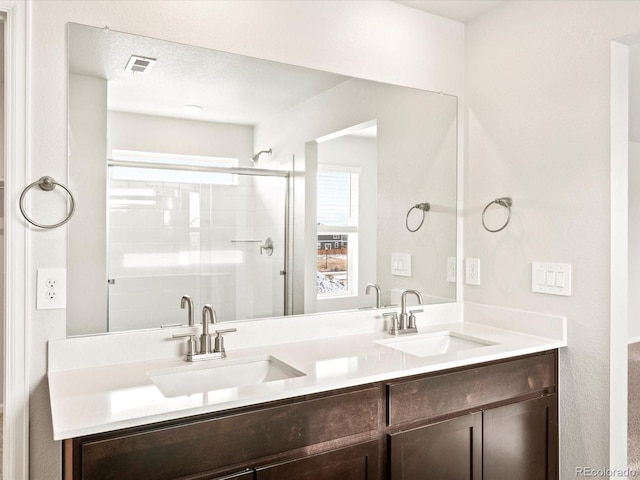 full bath featuring double vanity, a stall shower, a sink, and visible vents