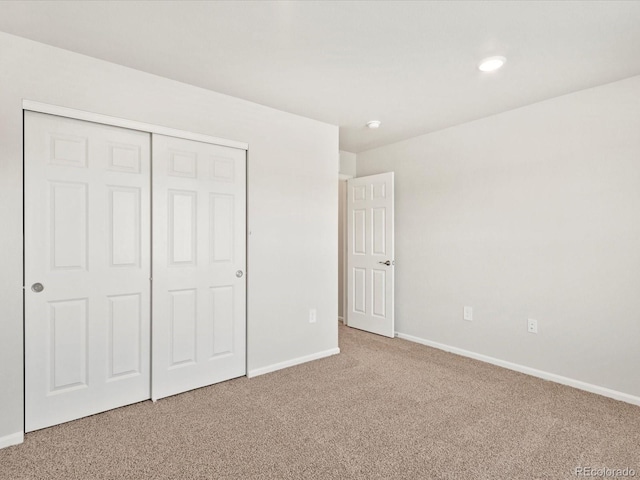 unfurnished bedroom with carpet floors, a closet, and baseboards