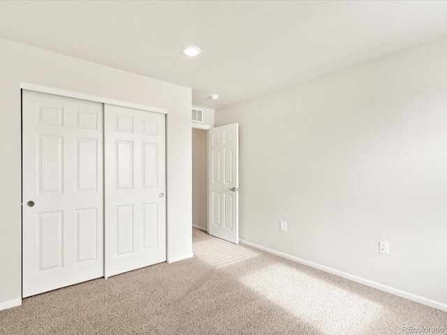 unfurnished bedroom with carpet floors, a closet, visible vents, and baseboards