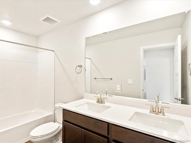 full bathroom with toilet, double vanity, visible vents, and a sink