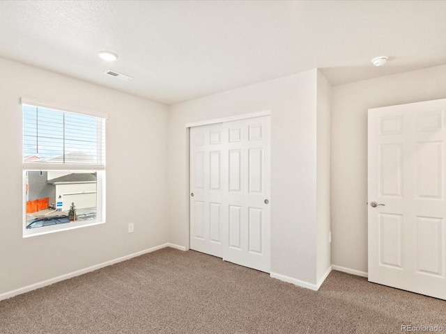 unfurnished bedroom with carpet floors, a closet, visible vents, and baseboards