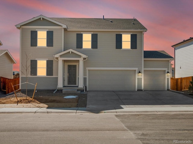 view of front facade with driveway, an attached garage, fence, and a shingled roof