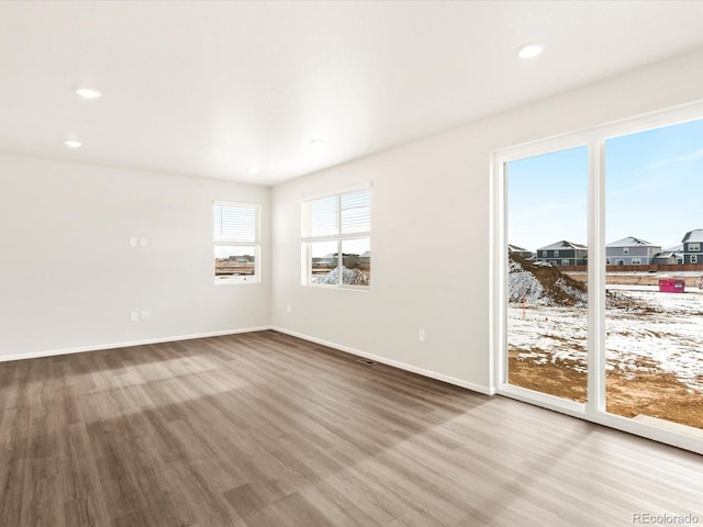 unfurnished room with baseboards, wood finished floors, and recessed lighting