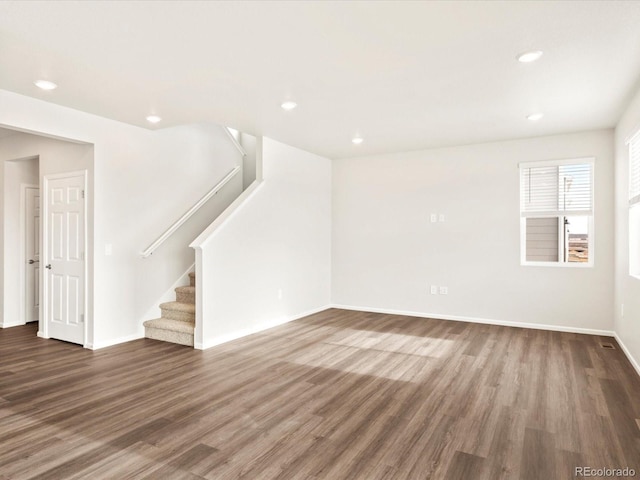 unfurnished living room with baseboards, stairway, wood finished floors, and recessed lighting