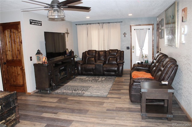 living room with a fireplace, dark wood-type flooring, and ceiling fan