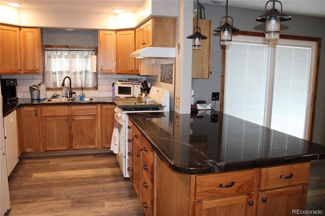 kitchen featuring sink, white appliances, hanging light fixtures, dark hardwood / wood-style flooring, and decorative backsplash