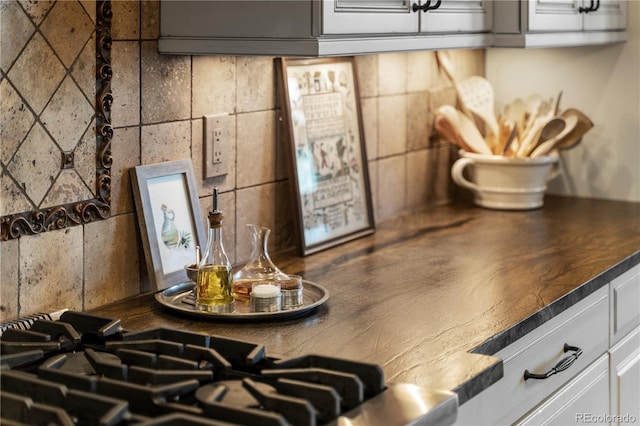 kitchen view of dark countertops, white cabinets, and tasteful backsplash