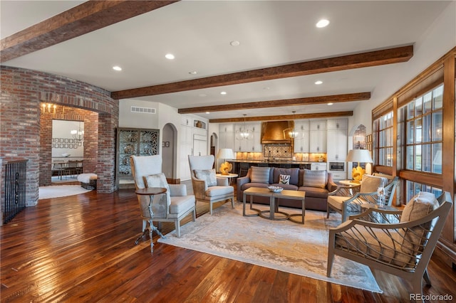 living area with arched walkways, wood-type flooring, beamed ceiling, brick wall, and recessed lighting