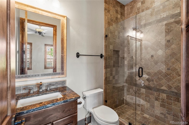 bathroom featuring toilet, a stall shower, vanity, and ceiling fan