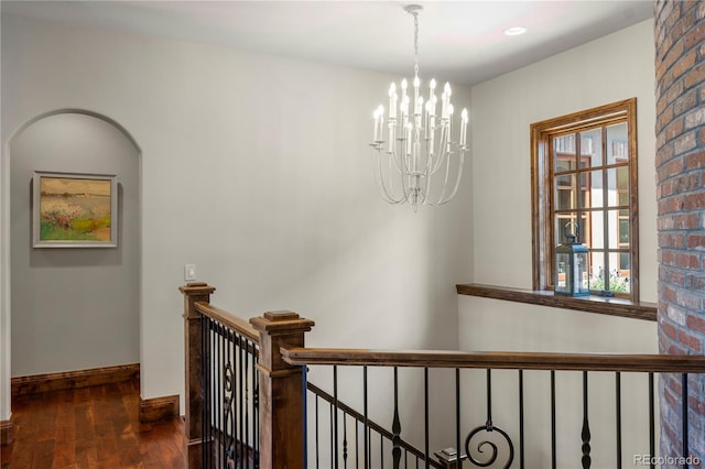 hall with wood finished floors, an upstairs landing, a chandelier, and baseboards