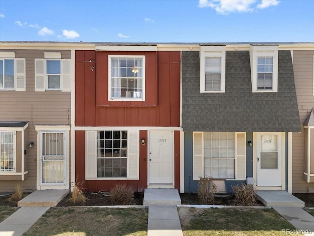 townhome / multi-family property with mansard roof, a shingled roof, and board and batten siding