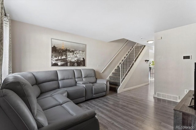 living room featuring visible vents, baseboards, dark wood-style floors, and stairway