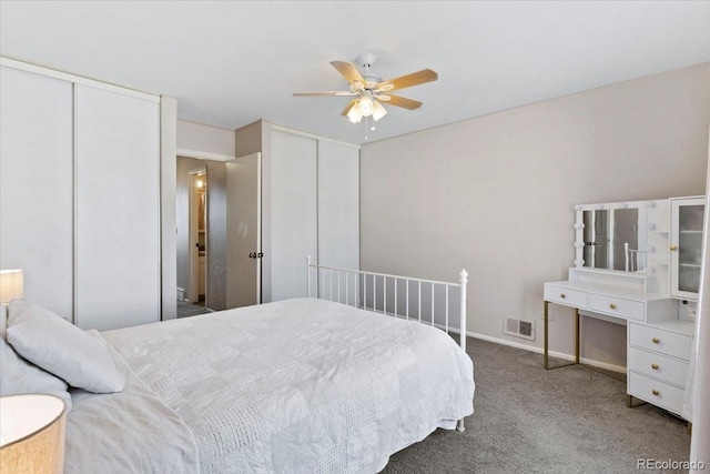 carpeted bedroom featuring visible vents, ceiling fan, two closets, and baseboards