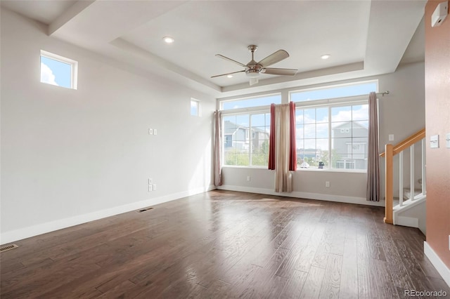 spare room featuring a tray ceiling, ceiling fan, and dark hardwood / wood-style flooring