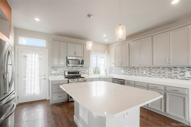 kitchen featuring dark wood-type flooring, a kitchen island, pendant lighting, stainless steel appliances, and sink