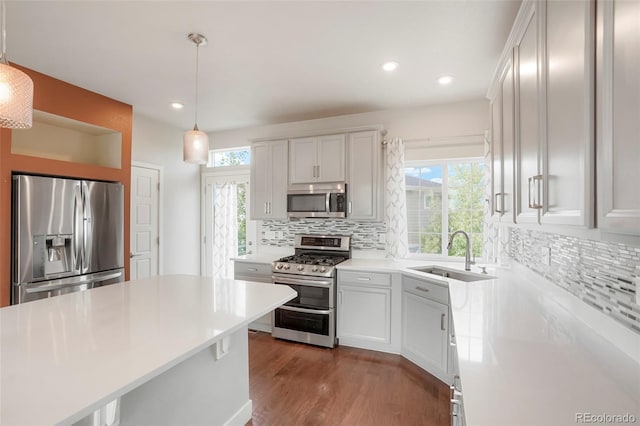 kitchen with white cabinets, sink, decorative light fixtures, appliances with stainless steel finishes, and dark hardwood / wood-style flooring