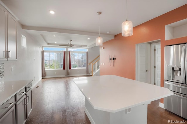 kitchen with stainless steel refrigerator with ice dispenser, hanging light fixtures, a kitchen island, dark hardwood / wood-style flooring, and ceiling fan