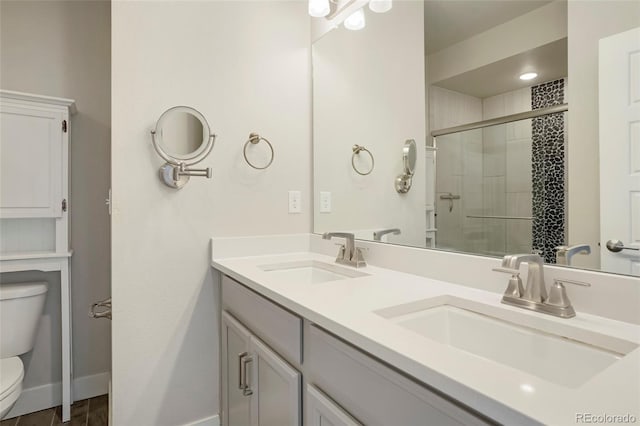 bathroom featuring wood-type flooring, vanity, toilet, and a shower with shower door