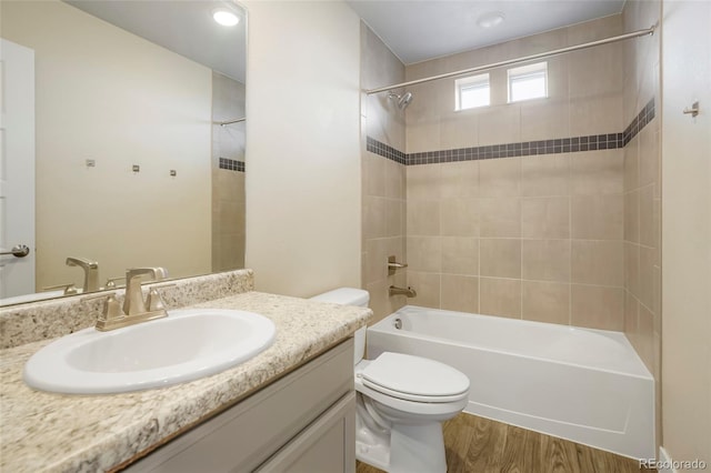 full bathroom featuring tiled shower / bath, hardwood / wood-style flooring, vanity, and toilet