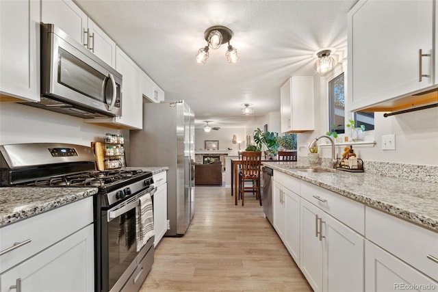 2954 E 101st Ave, Thornton, CO 80229 - kitchen featuring stainless steel appliances, a sink, light wood-type flooring, a ceiling fan, and white cabinetry